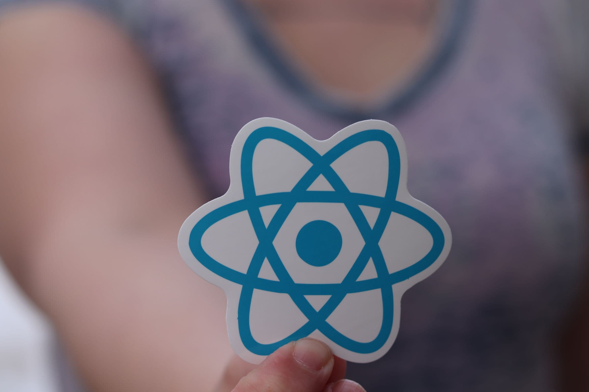 Een hand die een React logo sticker vasthoudt